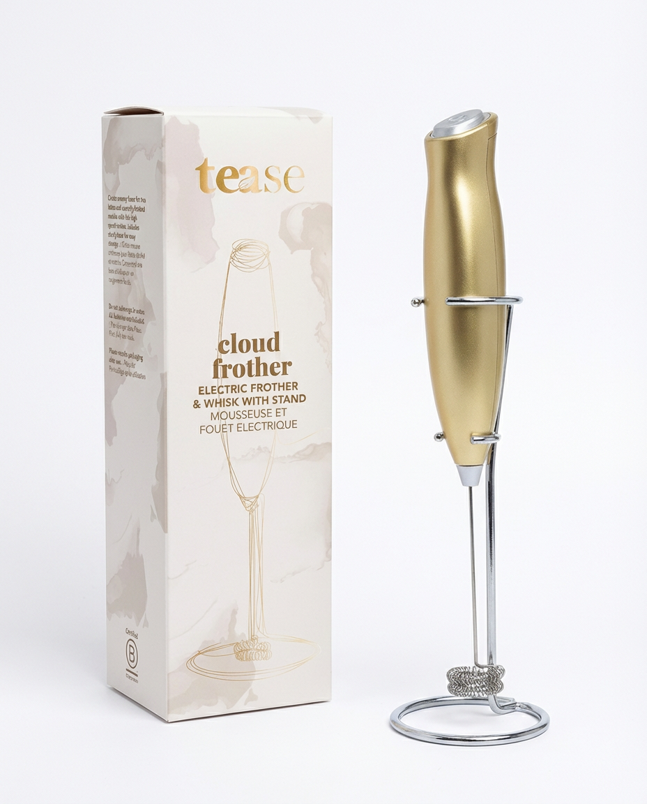 Gold-toned electric frother with sleek design and matching stand next to beige packaging box.